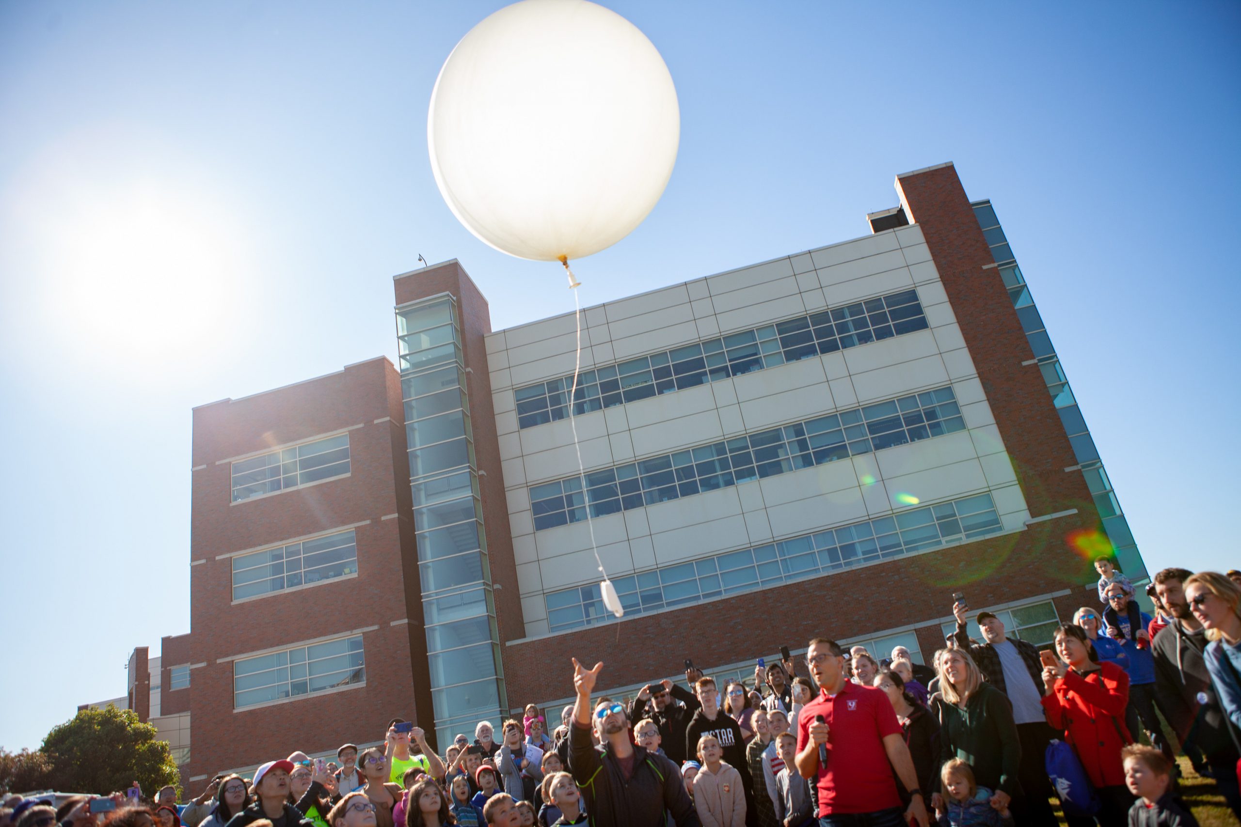 A weather balloon being launched in front of the National Weather Center building.