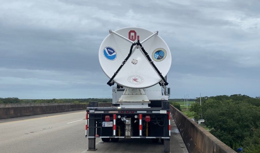 A mobile radar truck parked on a bridge with a cloudy sky behind it.