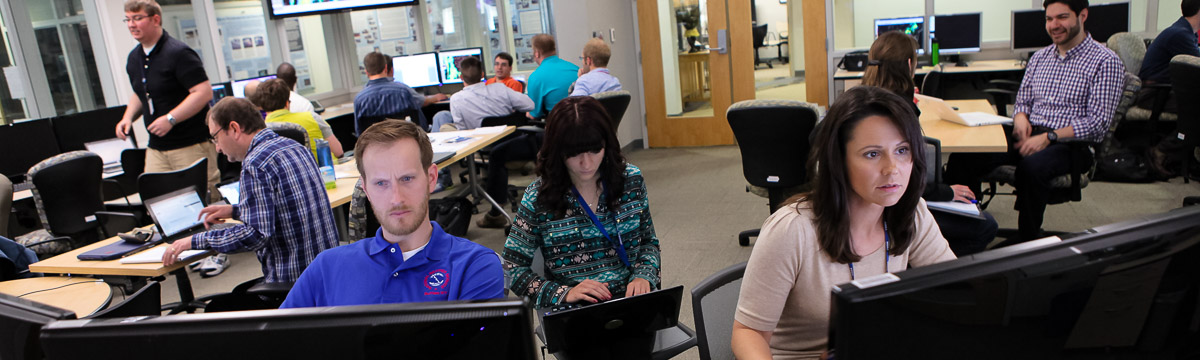 Many people working at computers in a single room.