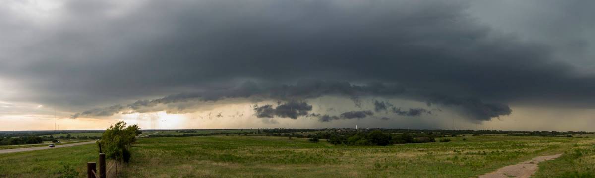 Wide angle photograph of a supercell thunderstorm over a rural area.